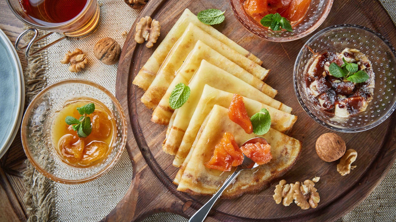 Тонкие блины с орехами и джемом на столе на Масленицу