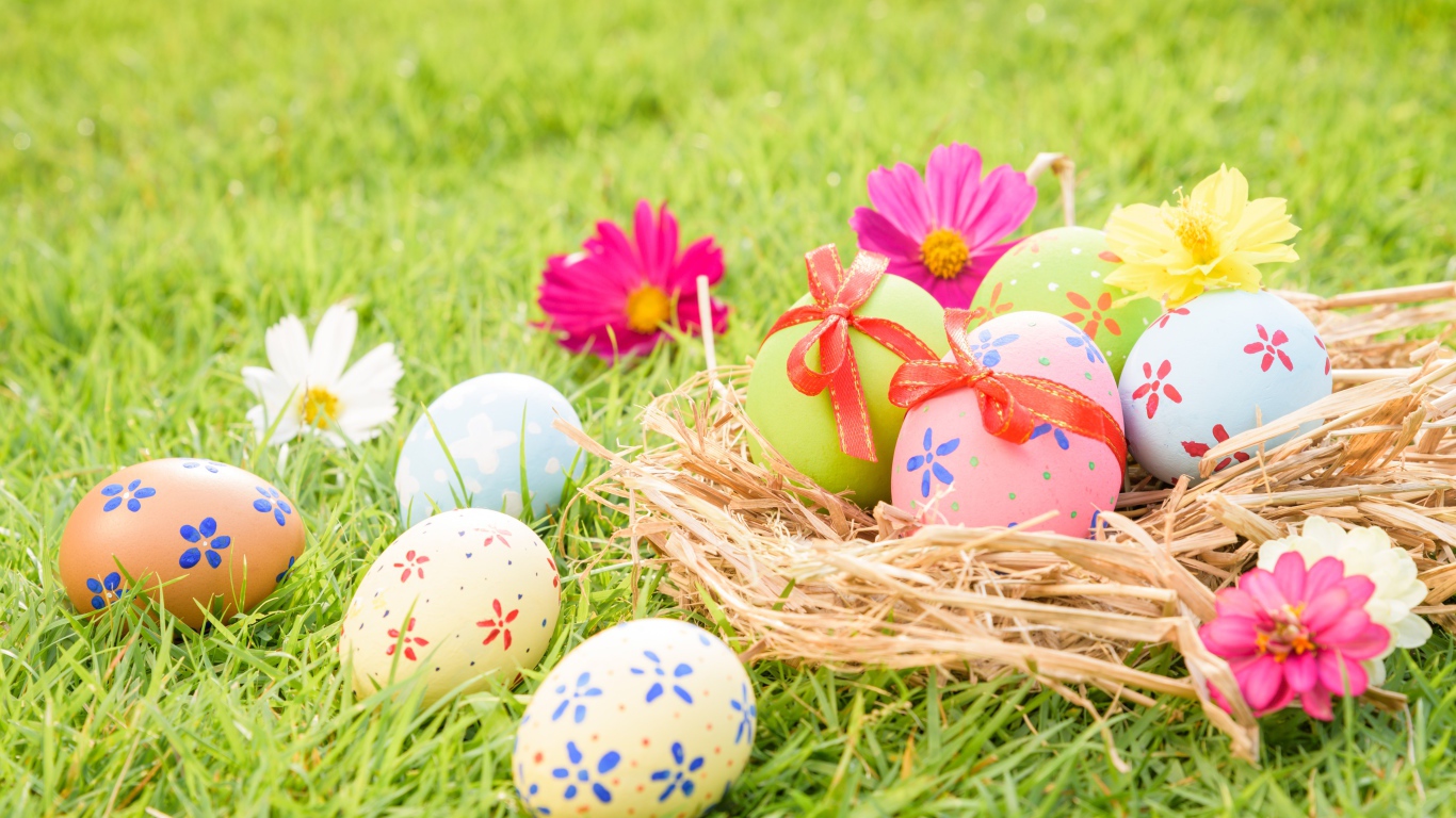 Разноцветные яйца в гнезде на зеленой траве на Пасху