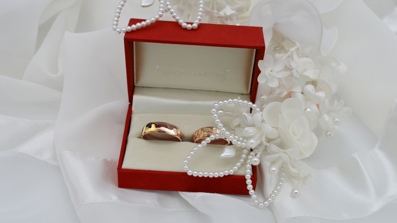 Золотые обручальные кольца в красной коробочке с украшениями