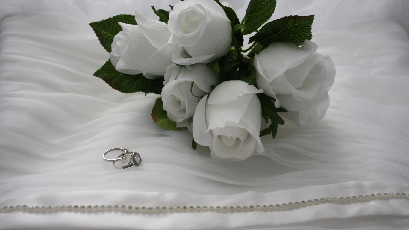 Белые бутоньерки с кольцами на белом покрывале 