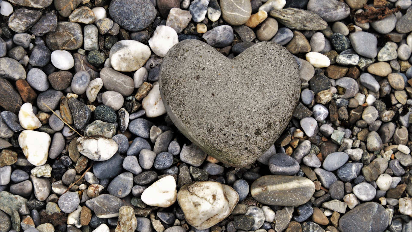 Большой камень в форме сердца лежит на морской гальке