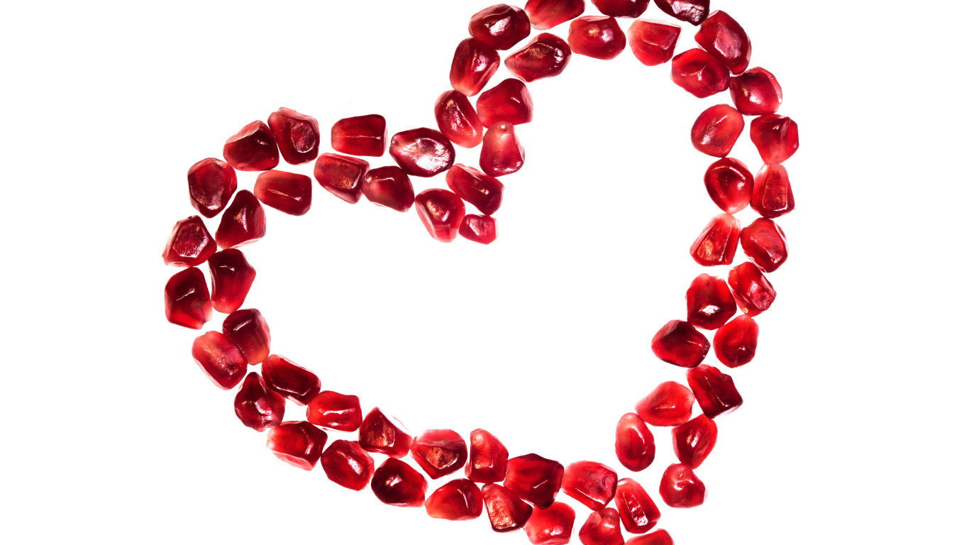 Сердце из гранатовых зерен на белом фоне