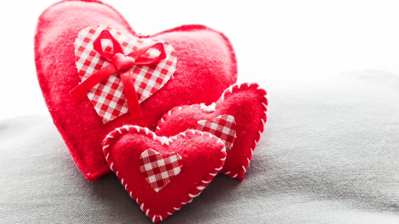 Сердечки из ткани лежат на серой поверхности 