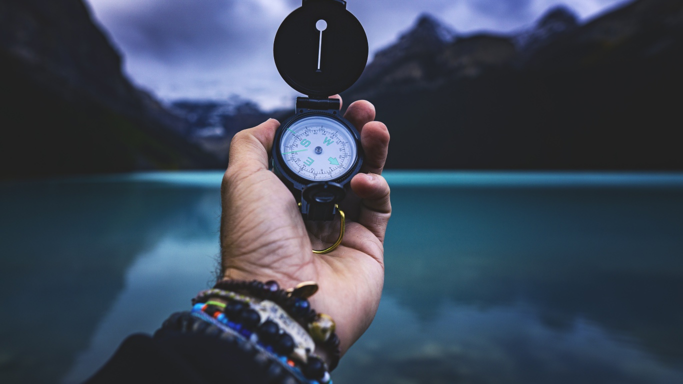 Компас в руке у мужчины на фоне гор 