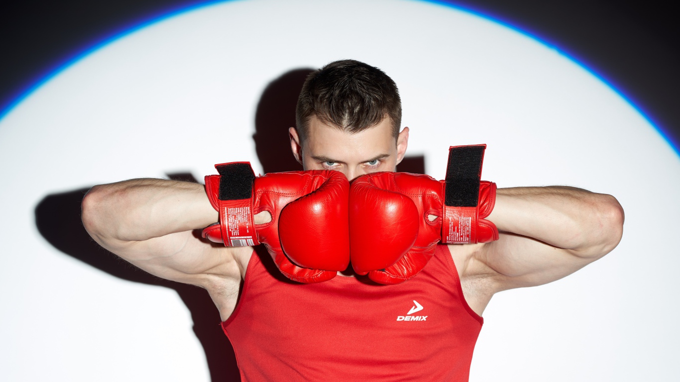 Мужчина боксер с красных перчатках в свете прожектора 