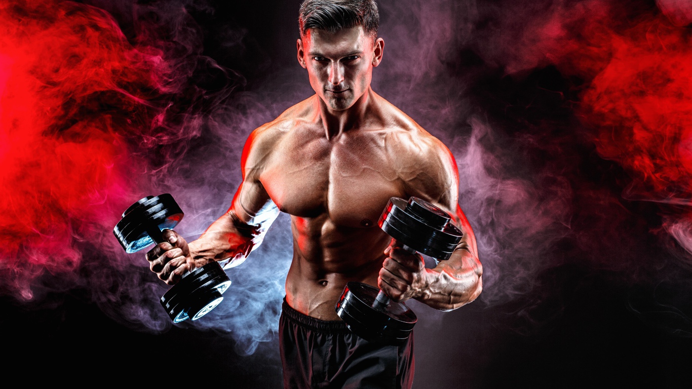 Muscular man with dumbbells in hands on a black background with smoke