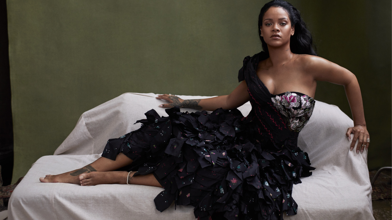 Певица Рианна в черном платье на диване 