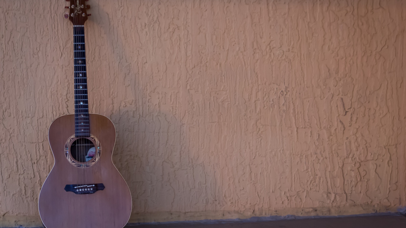 Шестиструнная гитара стоит у стены