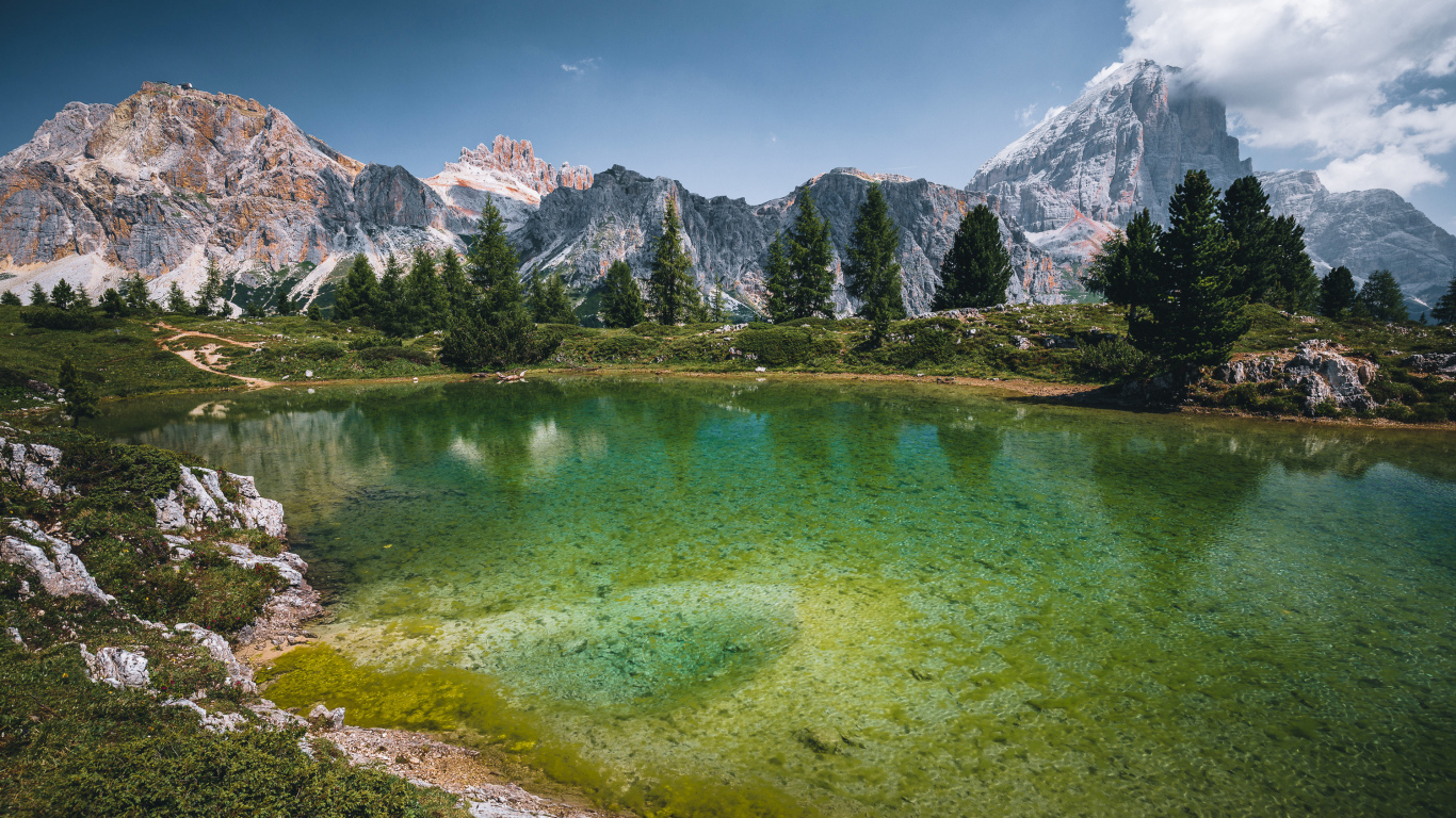 Озеро у заснеженных гор под небом с белыми облаками