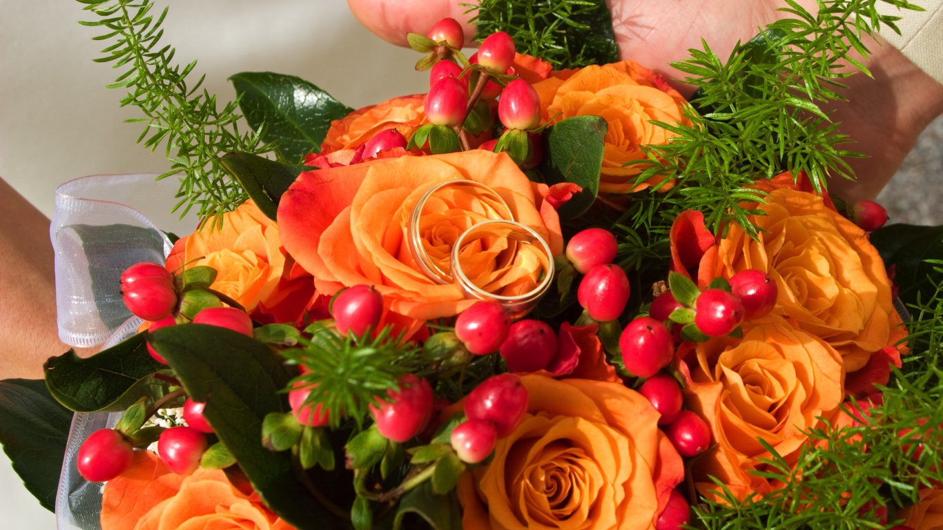 Букет оранжевых роз с красными ягодами и обручальными кольцами