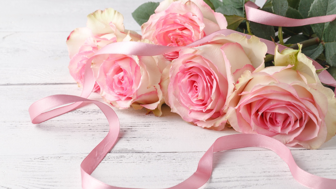 Букет розовых роз с лентой на белом столе 