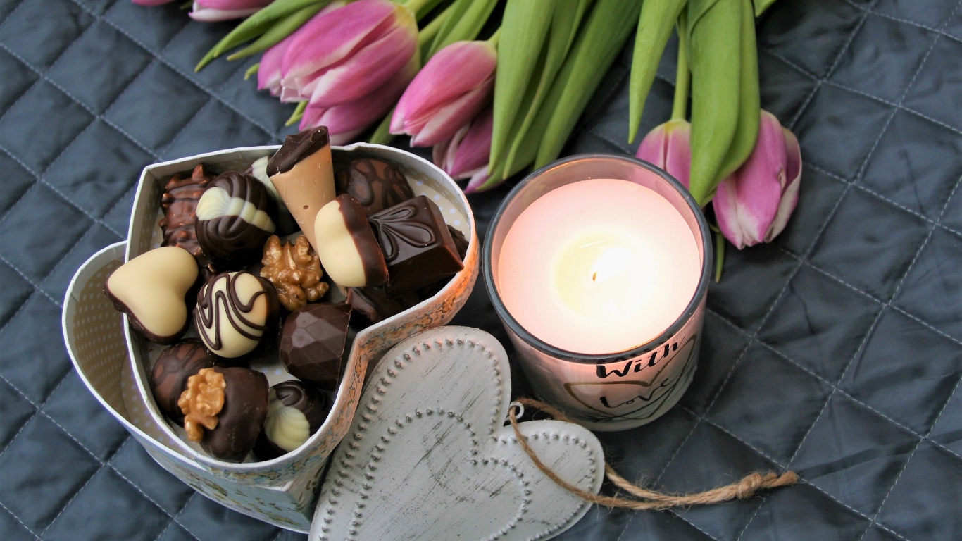 Букет розовых тюльпанов на кровати со свечой и коробкой конфет