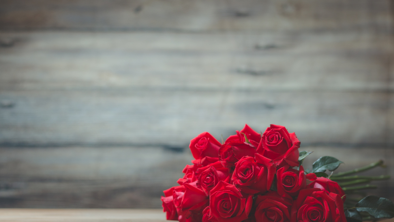 Букет красных роз на фоне деревянной стены 
