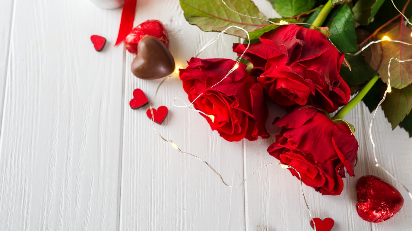 Букет красных роз с конфетами на столе