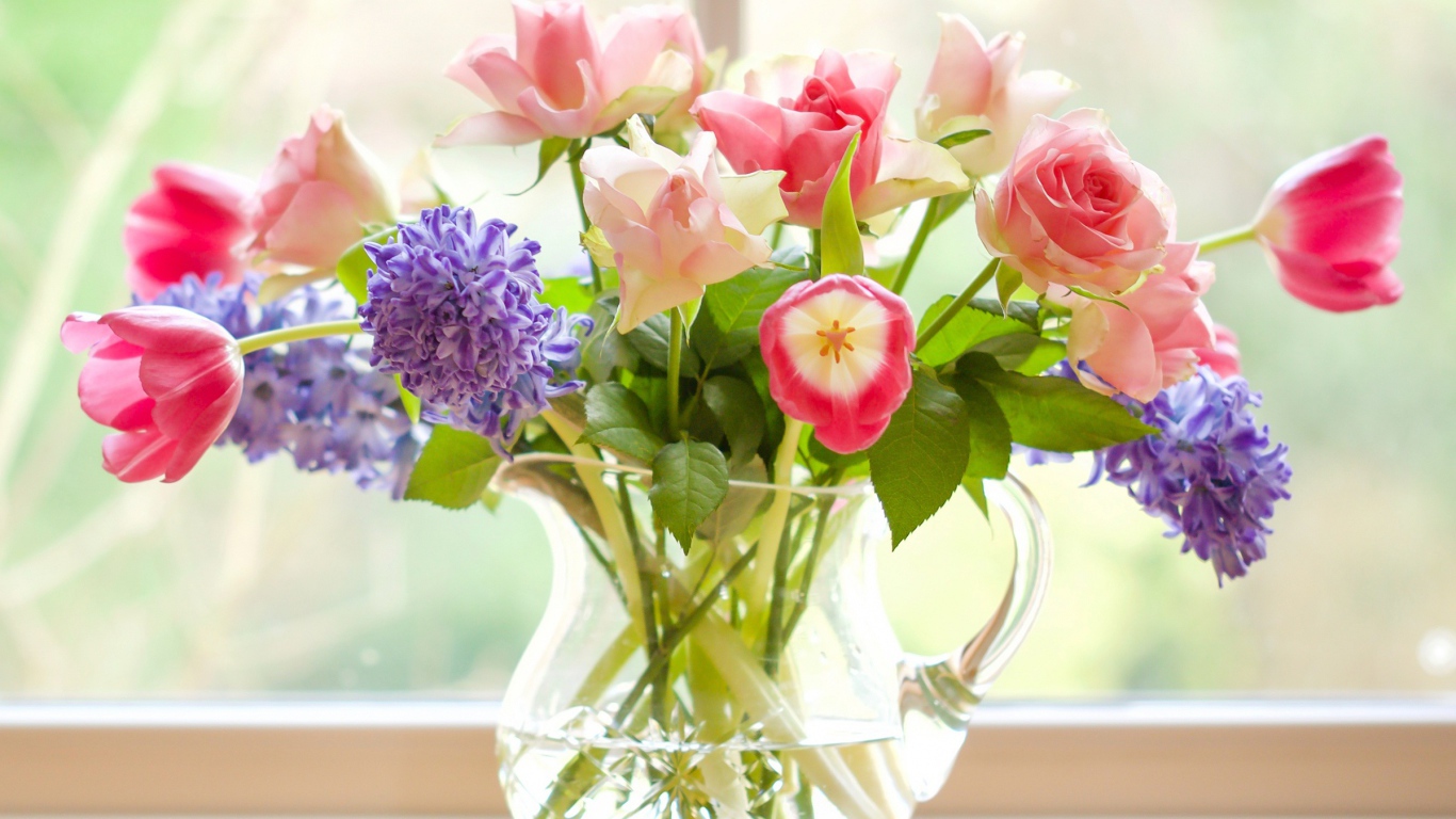 Букет роз, тюльпанов и гиацинтов в стеклянной вазе у окна