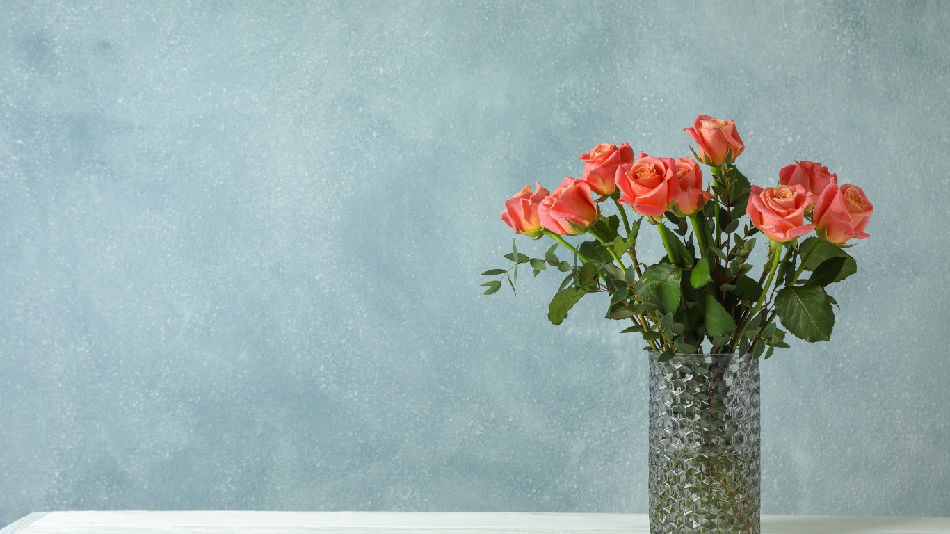 Букет роз в стеклянной вазе на сером фоне