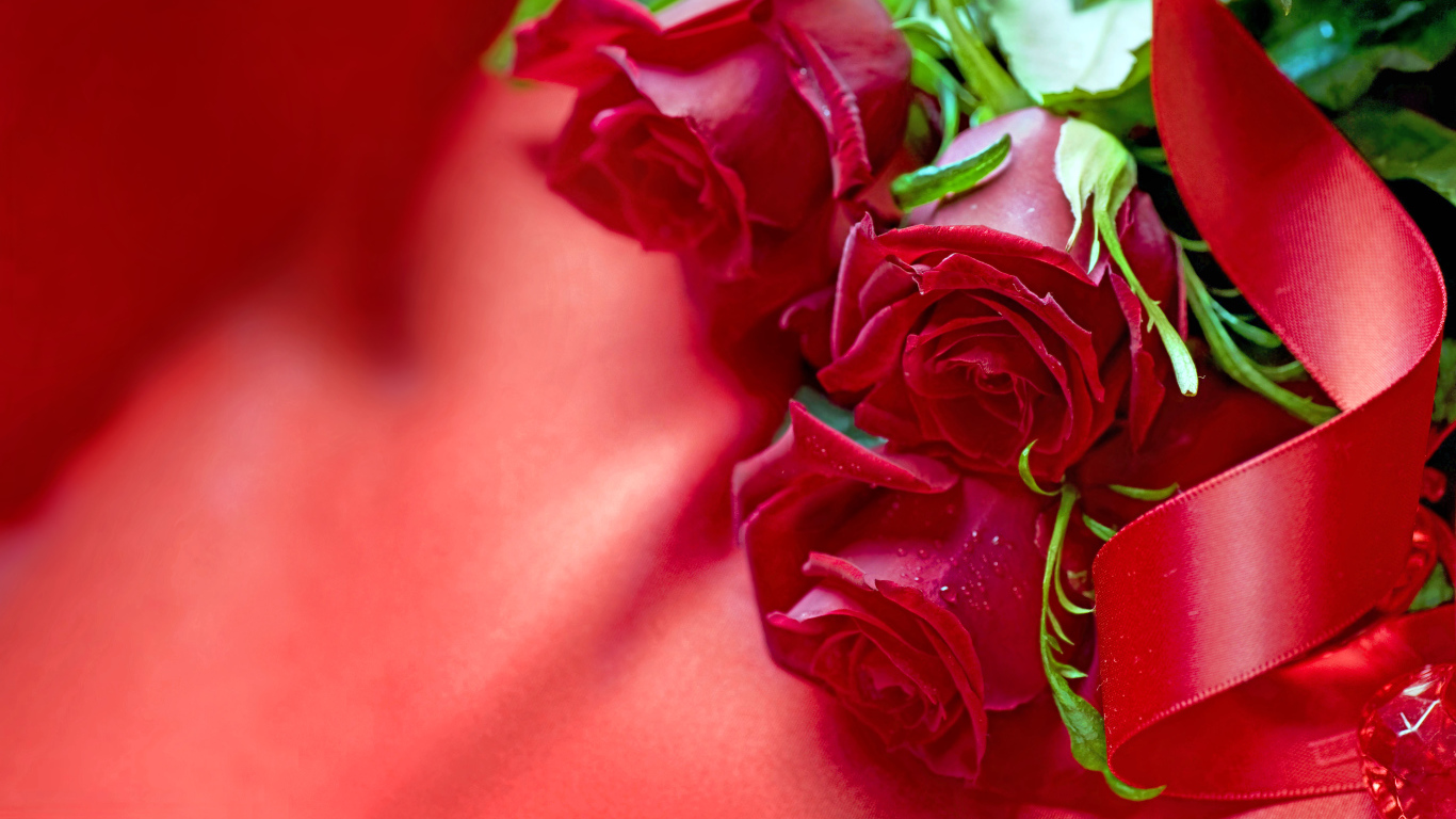 Три красные розы с атласной лентой на красной ткани
