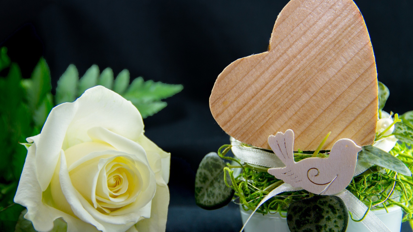 Деревянное сердце и белая роза на столе 