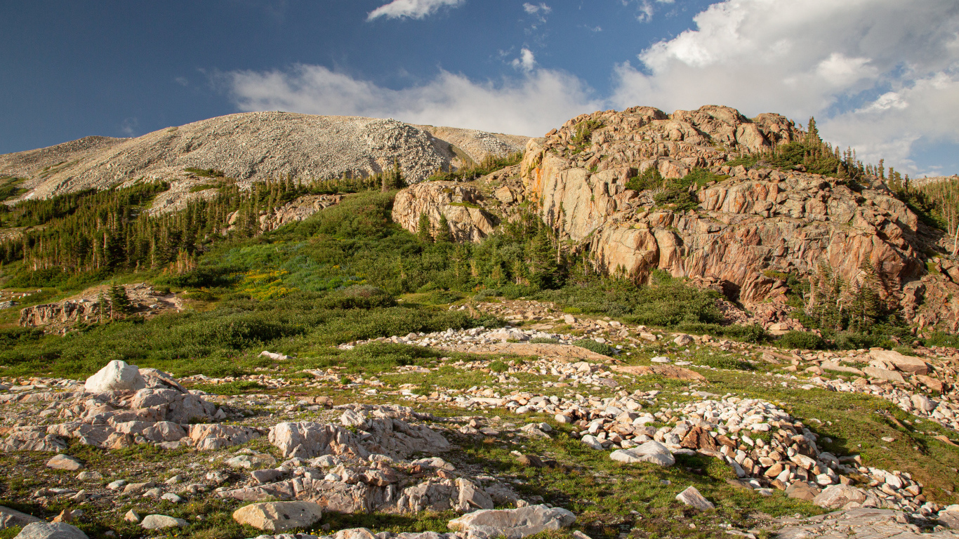 Высокие каменные горы под  голубым небом с белыми облаками