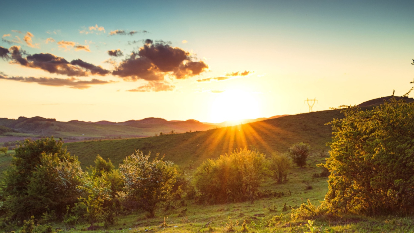 Яркое летнее солнце встает из-за гор 