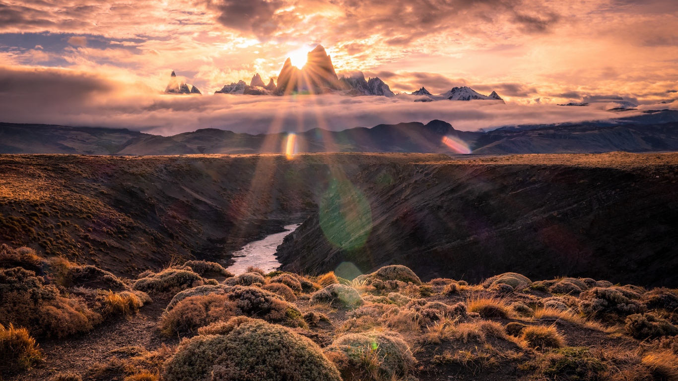 Лучи яркого солнца пробиваются сквозь вершину горы на рассвете 