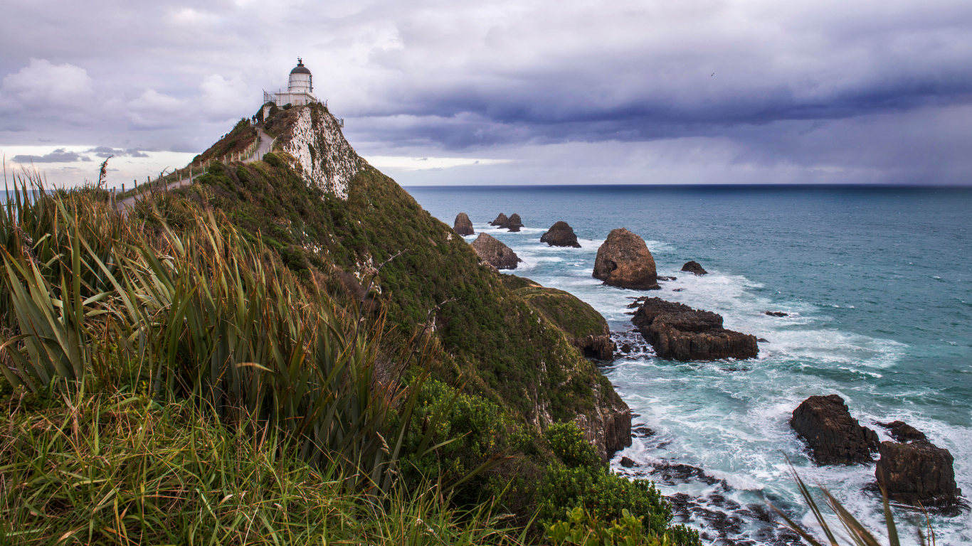 Маяк на вершине утеса у моря под грозовым небом
