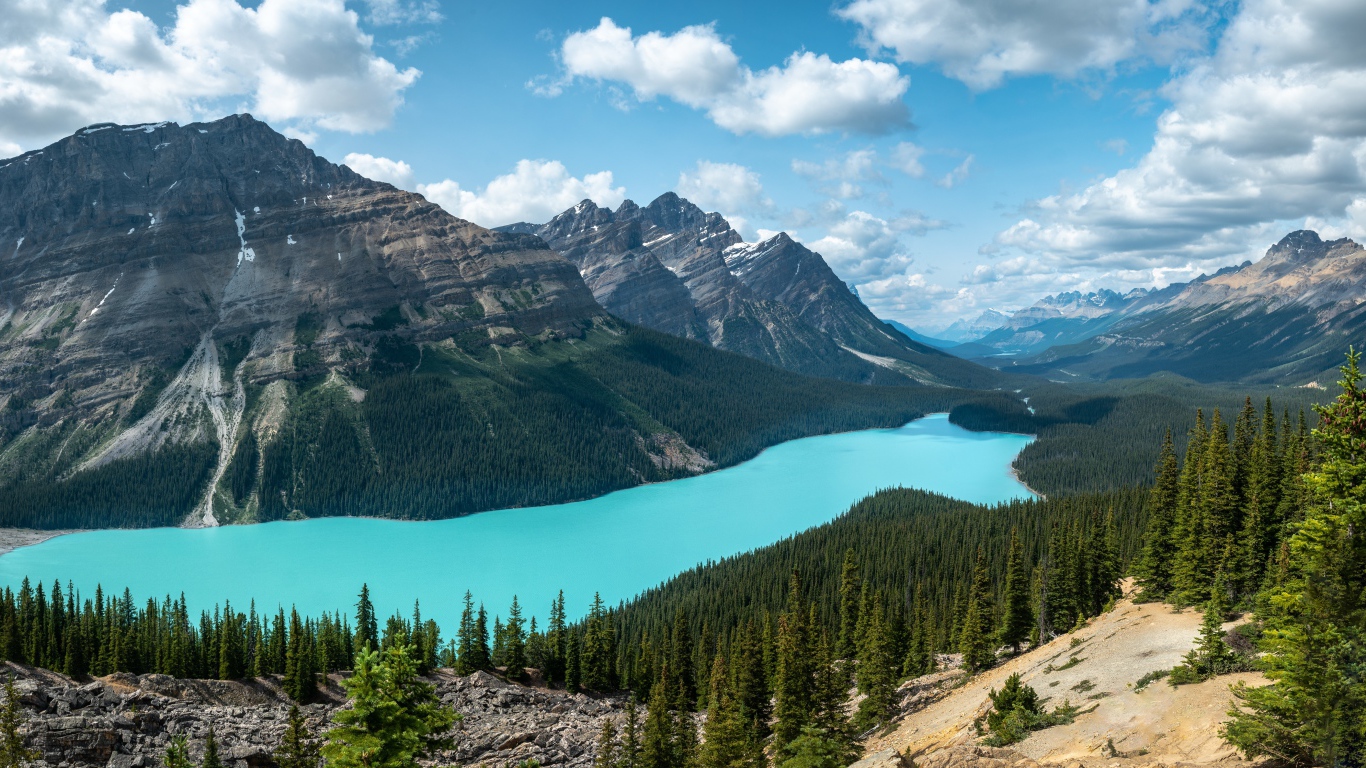 Тень от белых облаков на горном массиве у голубого озера