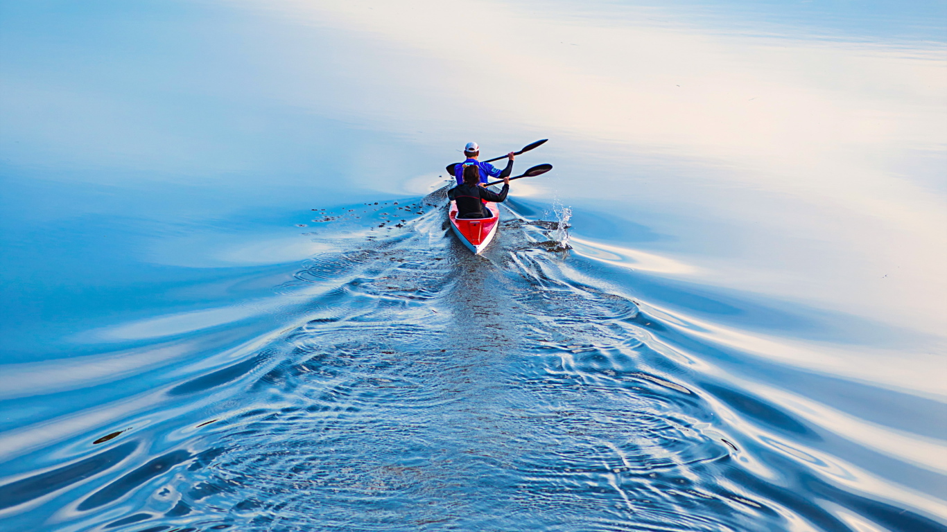 Два спортсмена на лодке плывут по реке 