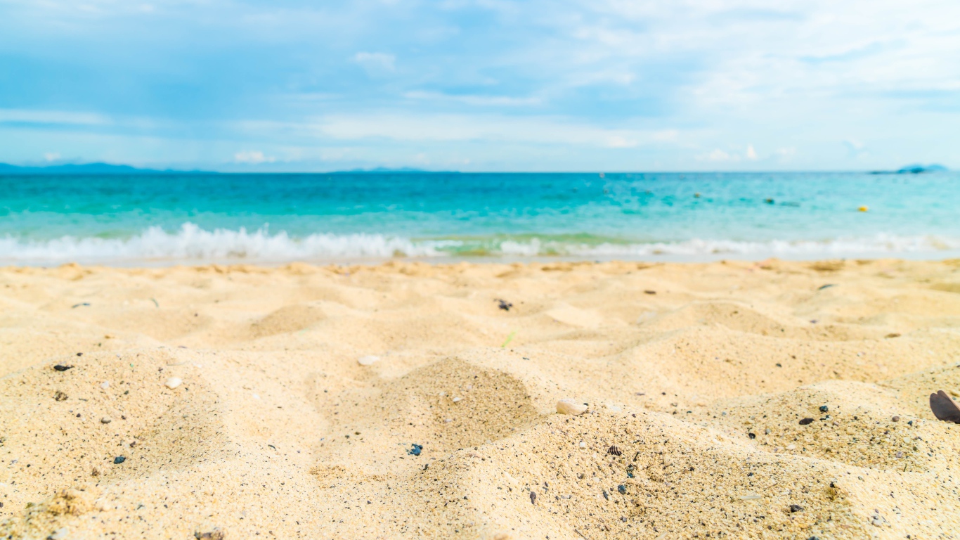 Горячий желтый песок на пляже у океана летом 