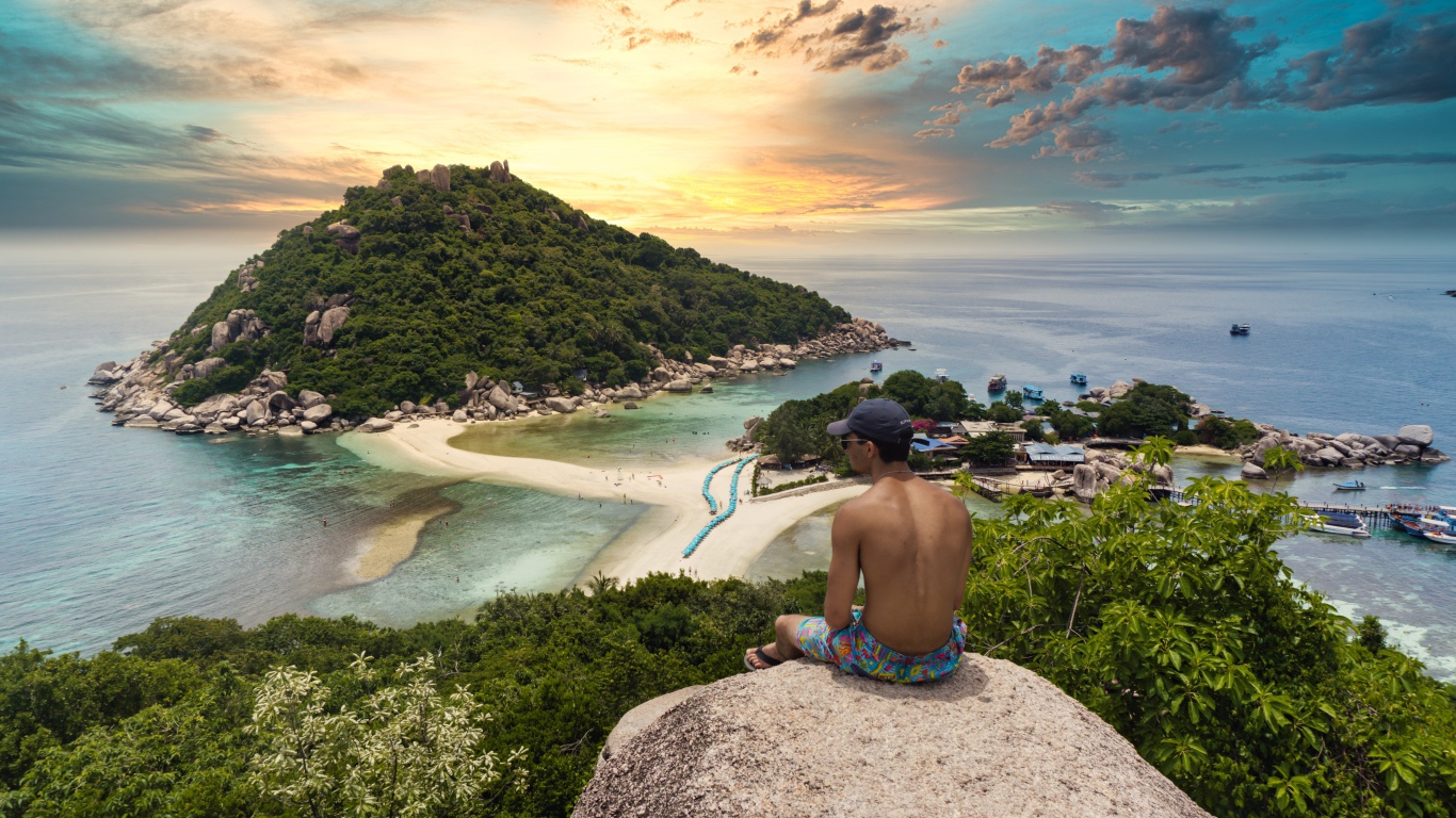 Мужчина сидит на краю скалы на закате 