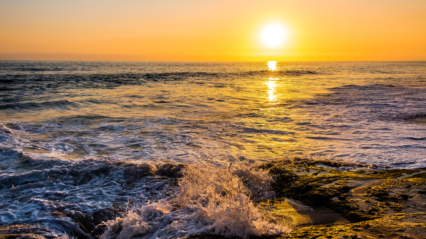 Белые волны бьются о берег на закате 