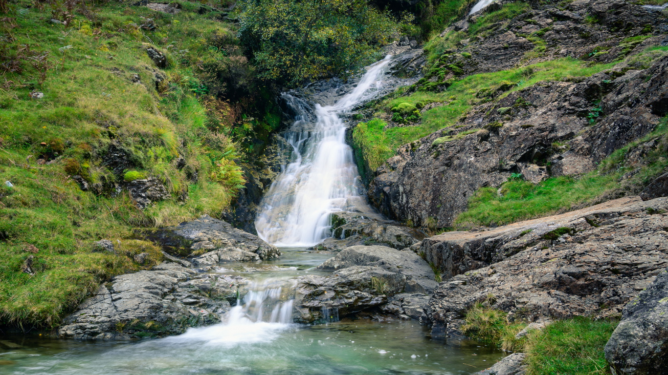 Горный ручей стекает по камням в реку 