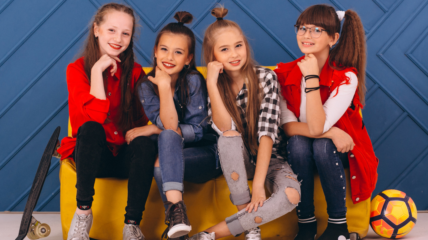 Четыре модных девочки сидят на диване 