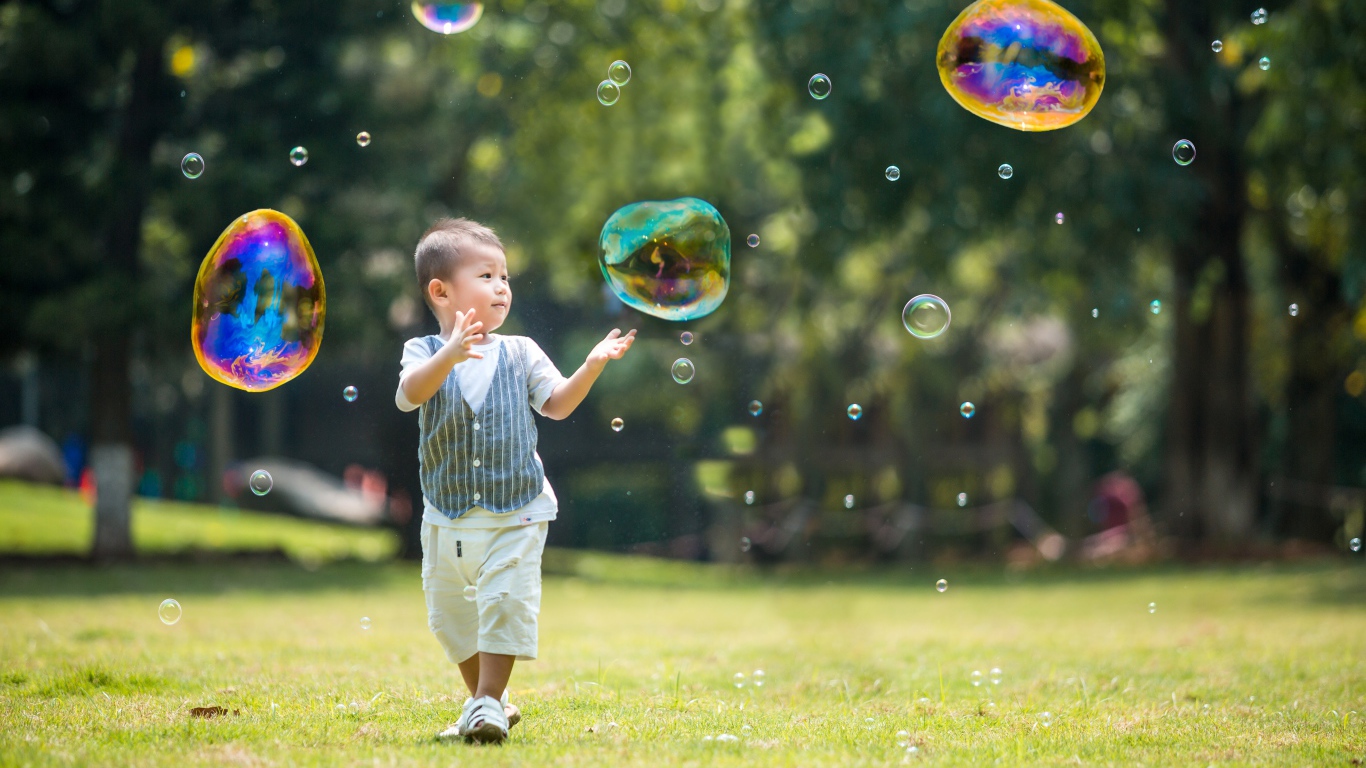 Маленький мальчик ловит мыльные пузыри