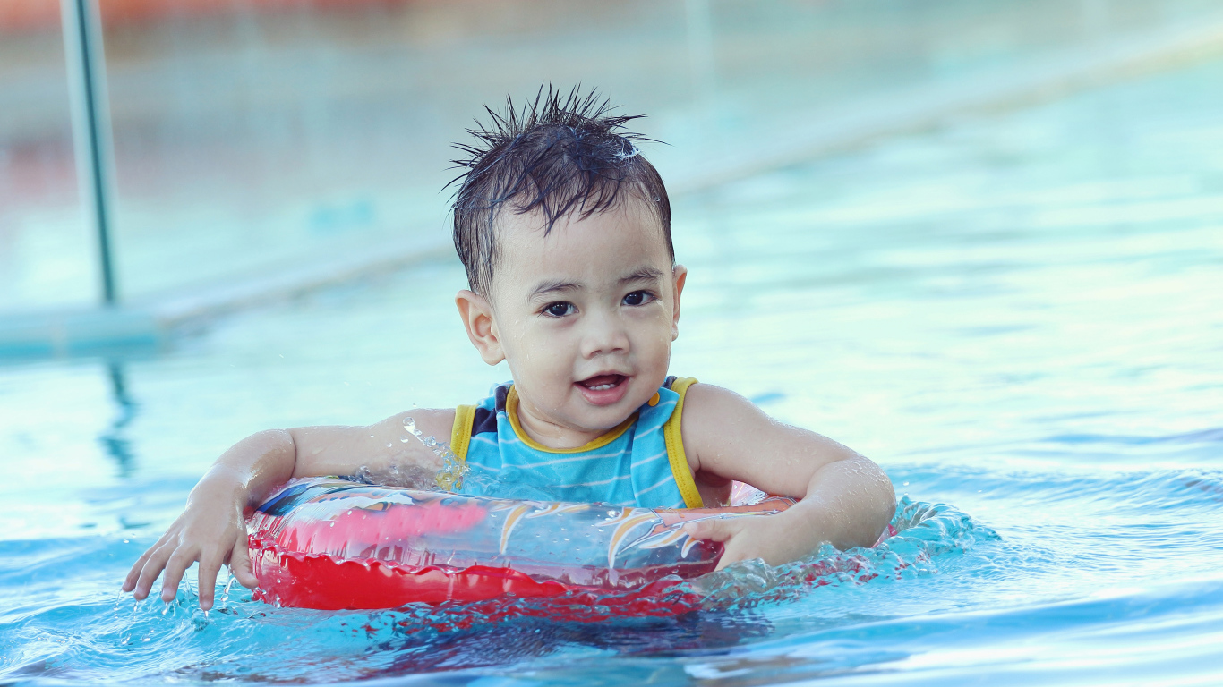 Маленький ребенок со спасательным кругом в бассейне 