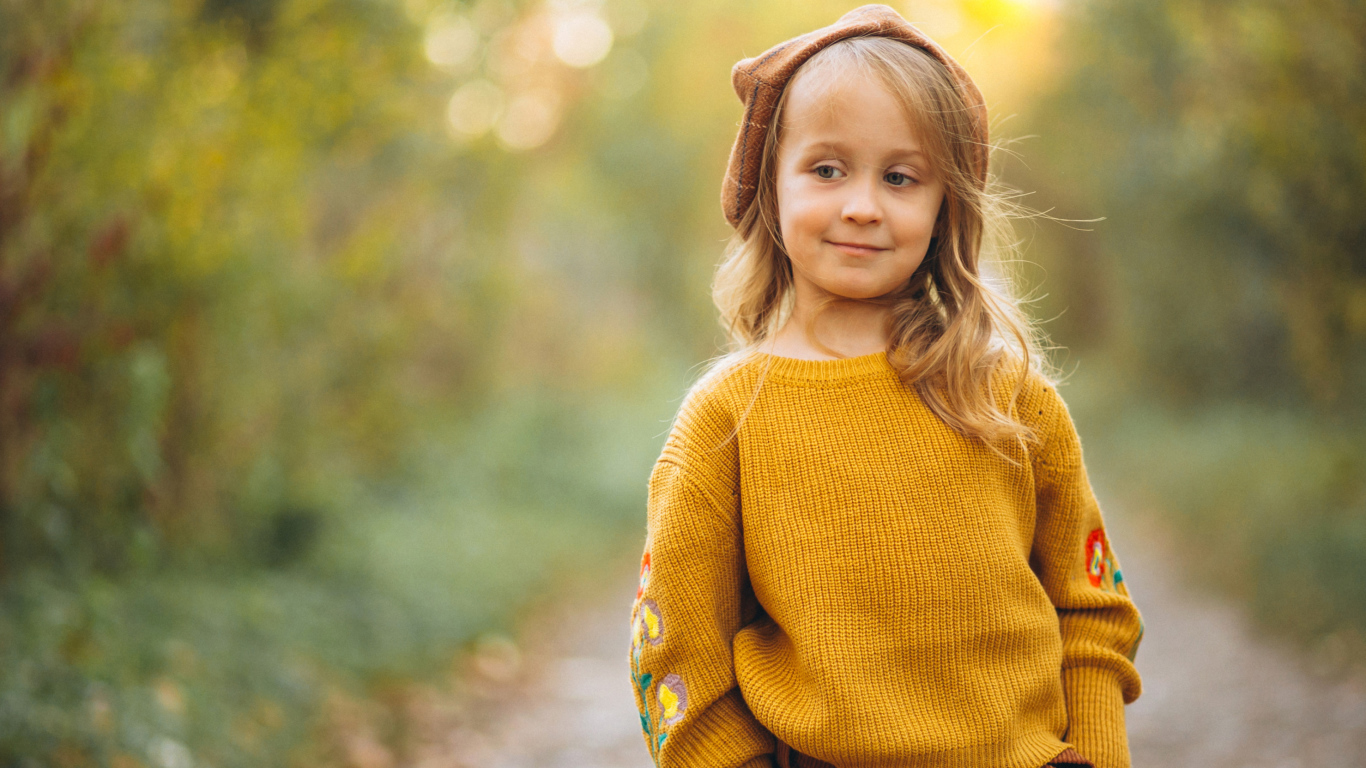 Маленькая девочка в свитере гуляет в лесу
