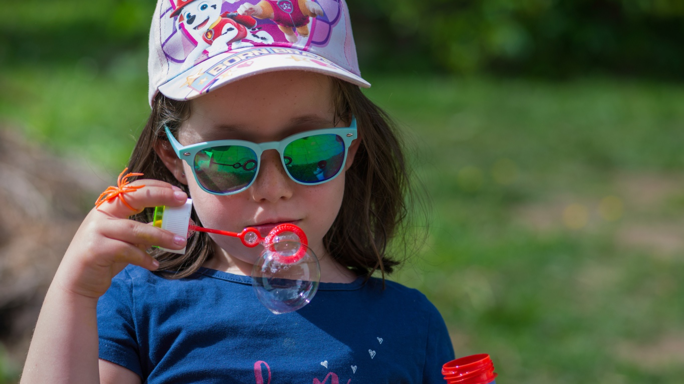 Маленькая девочка в очках с мыльными пузырями