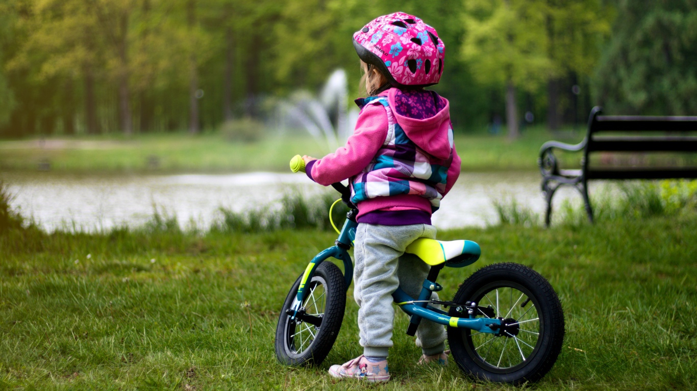 Маленькая девочка на велосипеде в парке 