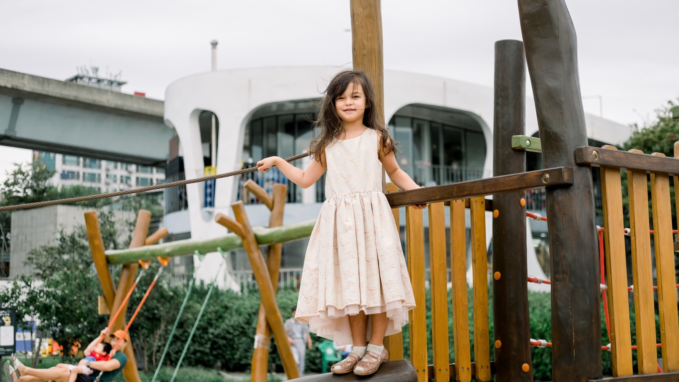 Маленькая девочка стоит на детской площадке 