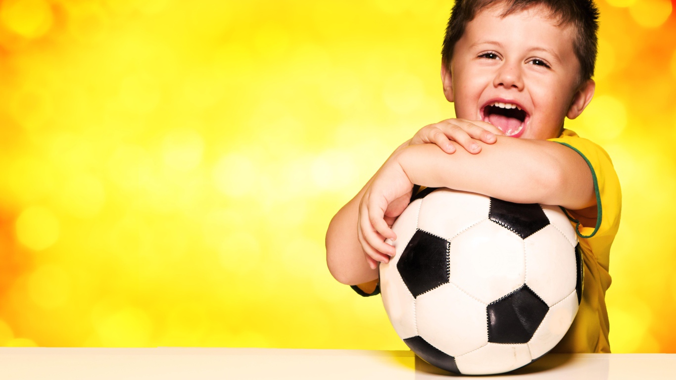 Маленький довольный мальчик с футбольным мячом