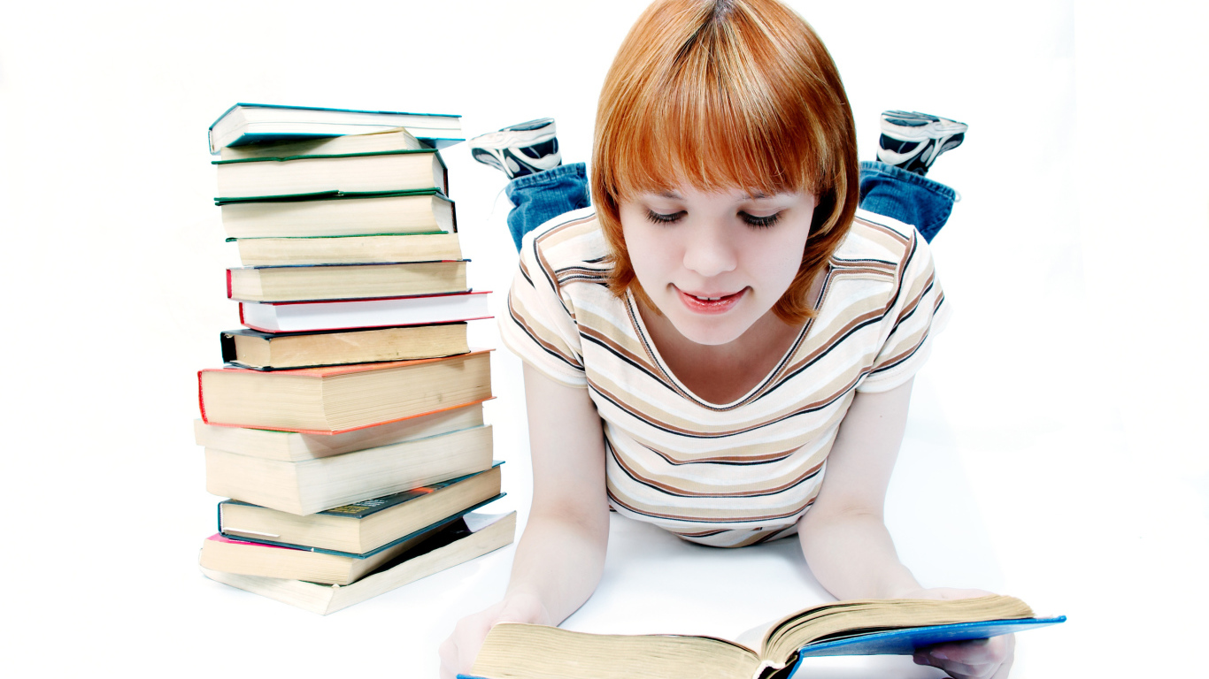 Рыжеволосая девочка школьница читает книги на белом фоне 