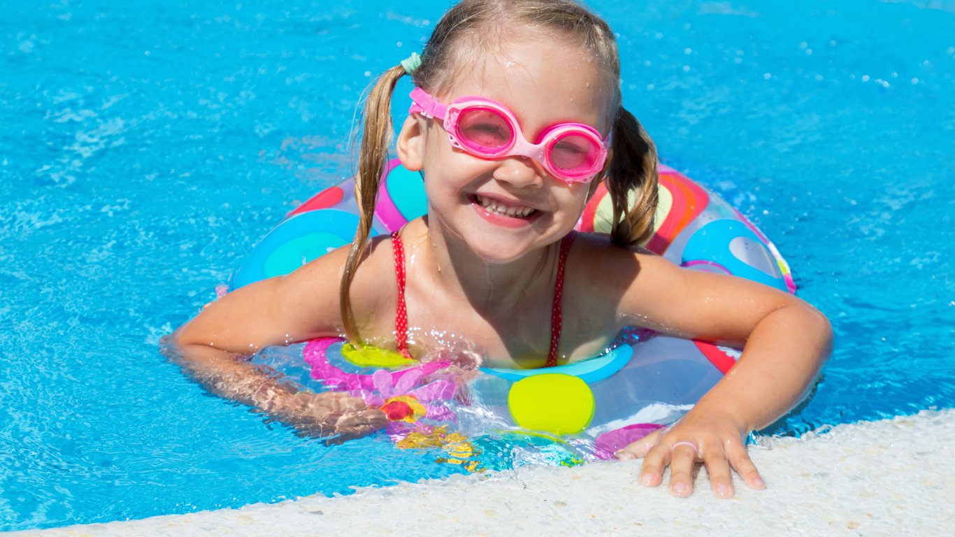 Улыбающаяся девочка с кругом в бассейне 