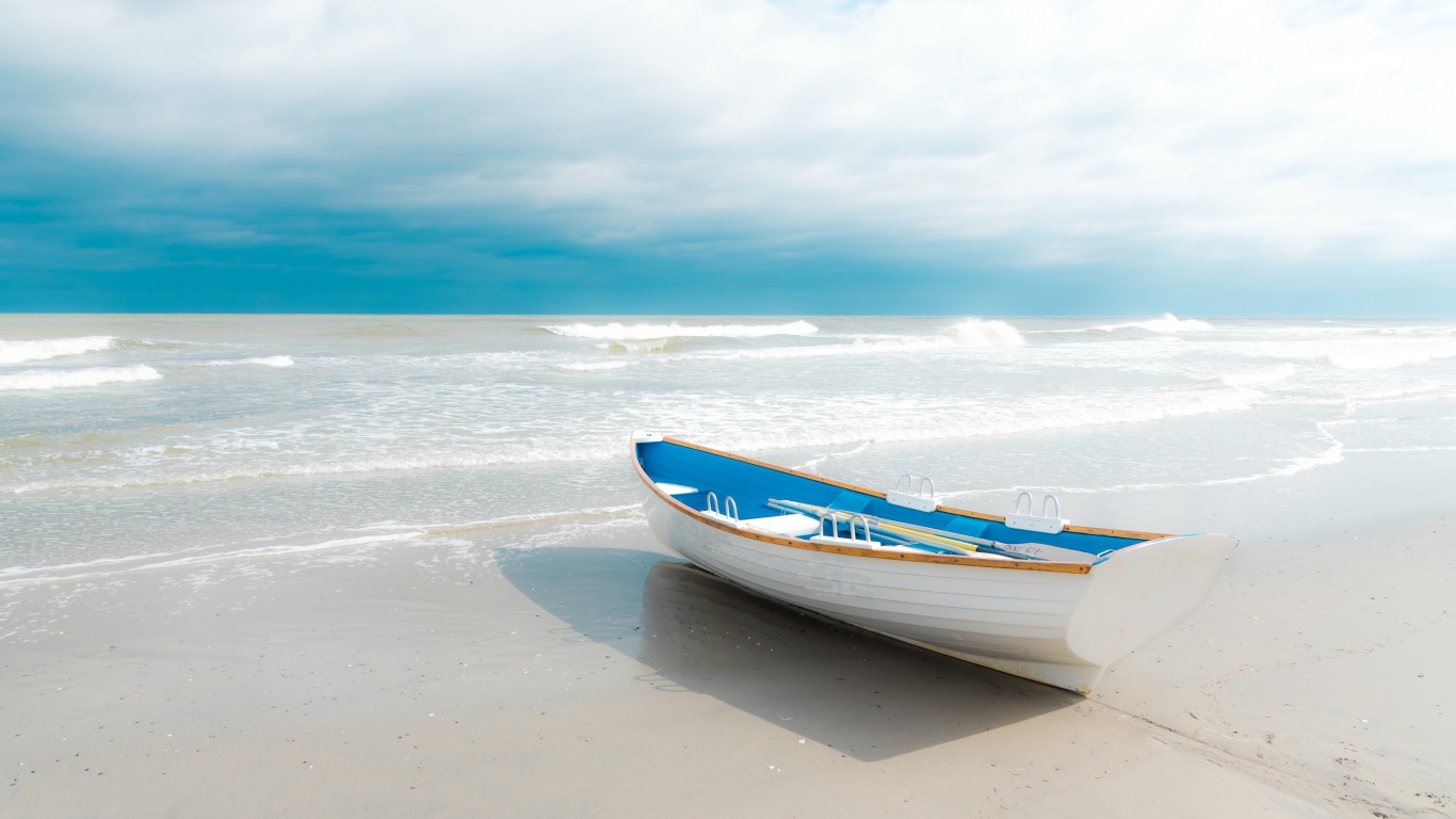 The boat stands on white sand by the sea