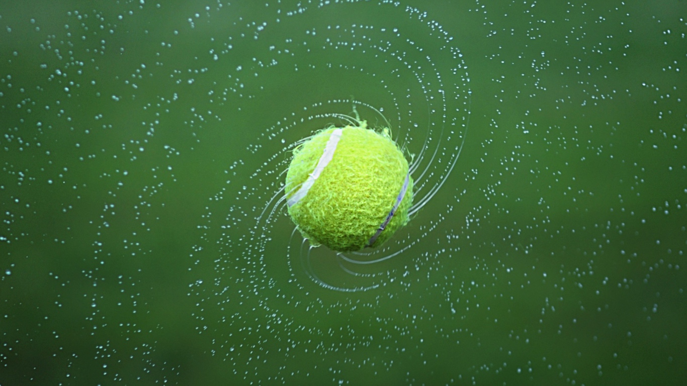 Tennis ball in splashing water on green background