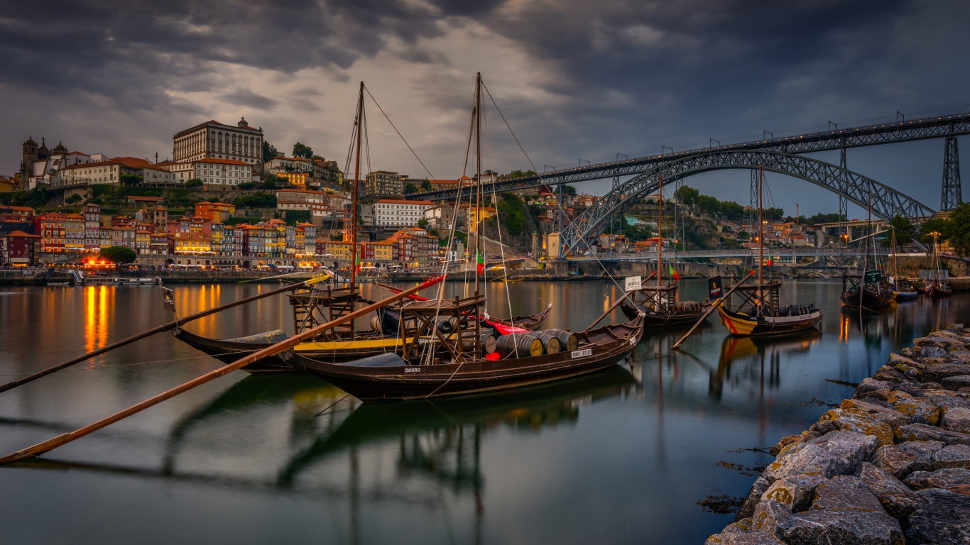 Лодки в порту на фоне моста и города на закате 