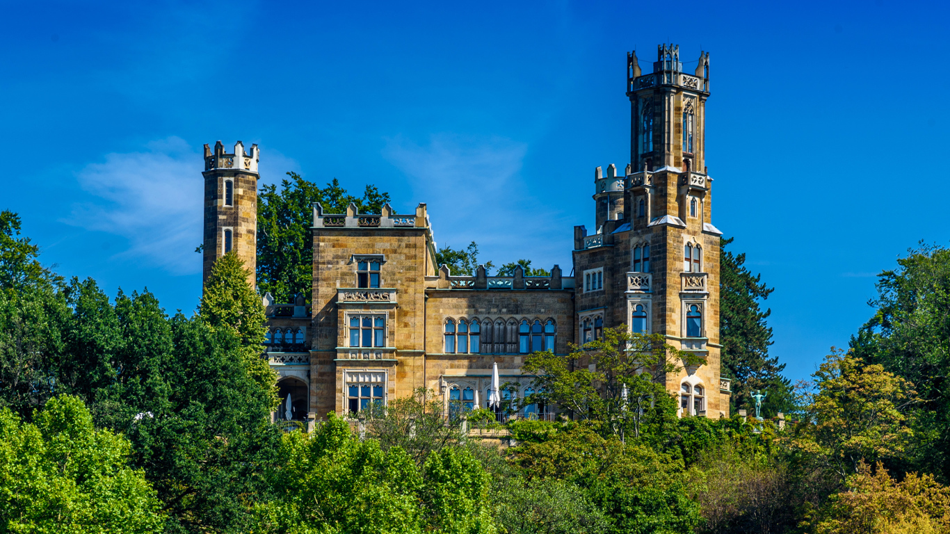 Старинный замок в зарослях деревьев на фоне голубого неба, Германия