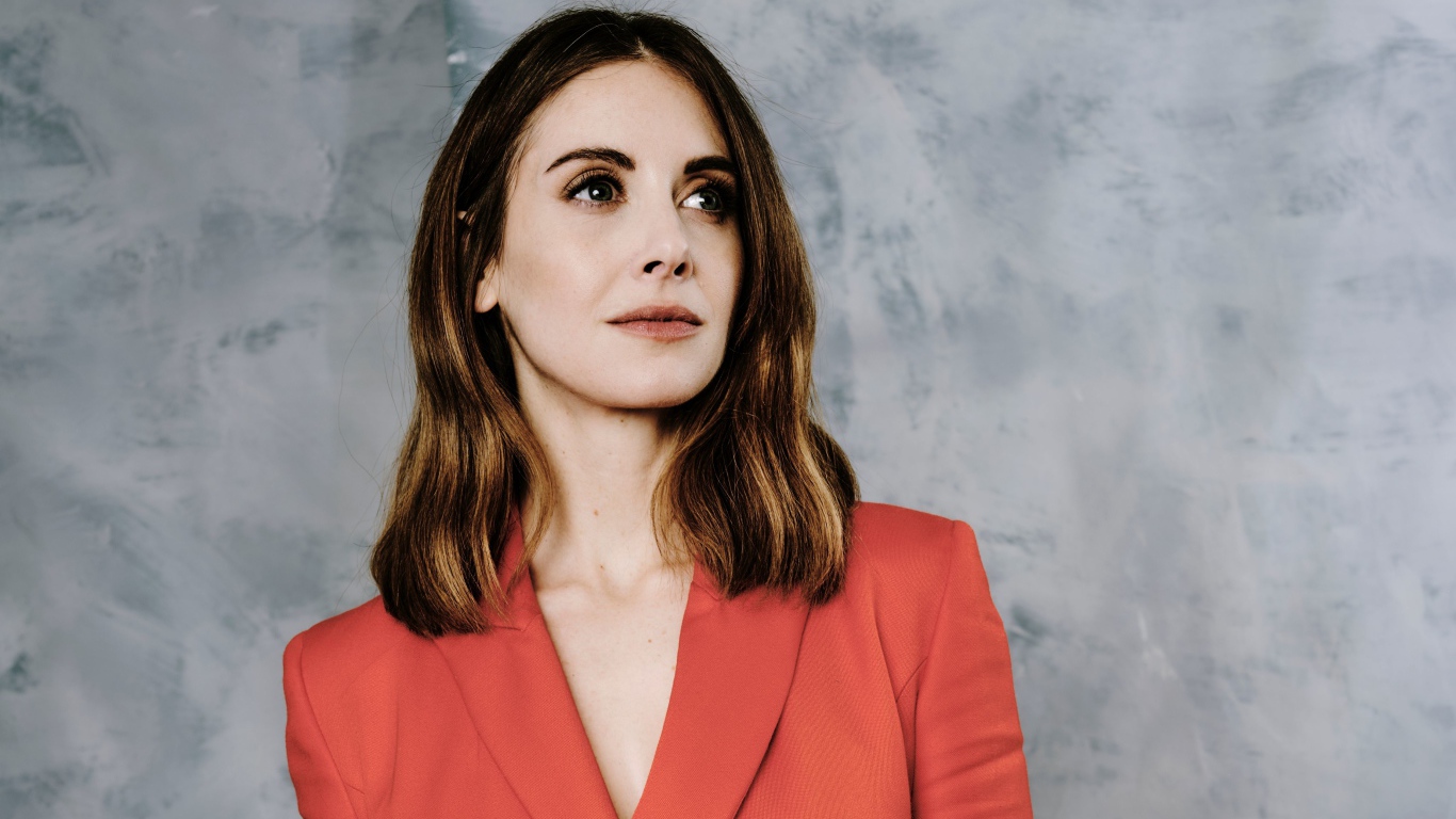 Актриса Элисон Бри в красном пиджаке на сером фоне