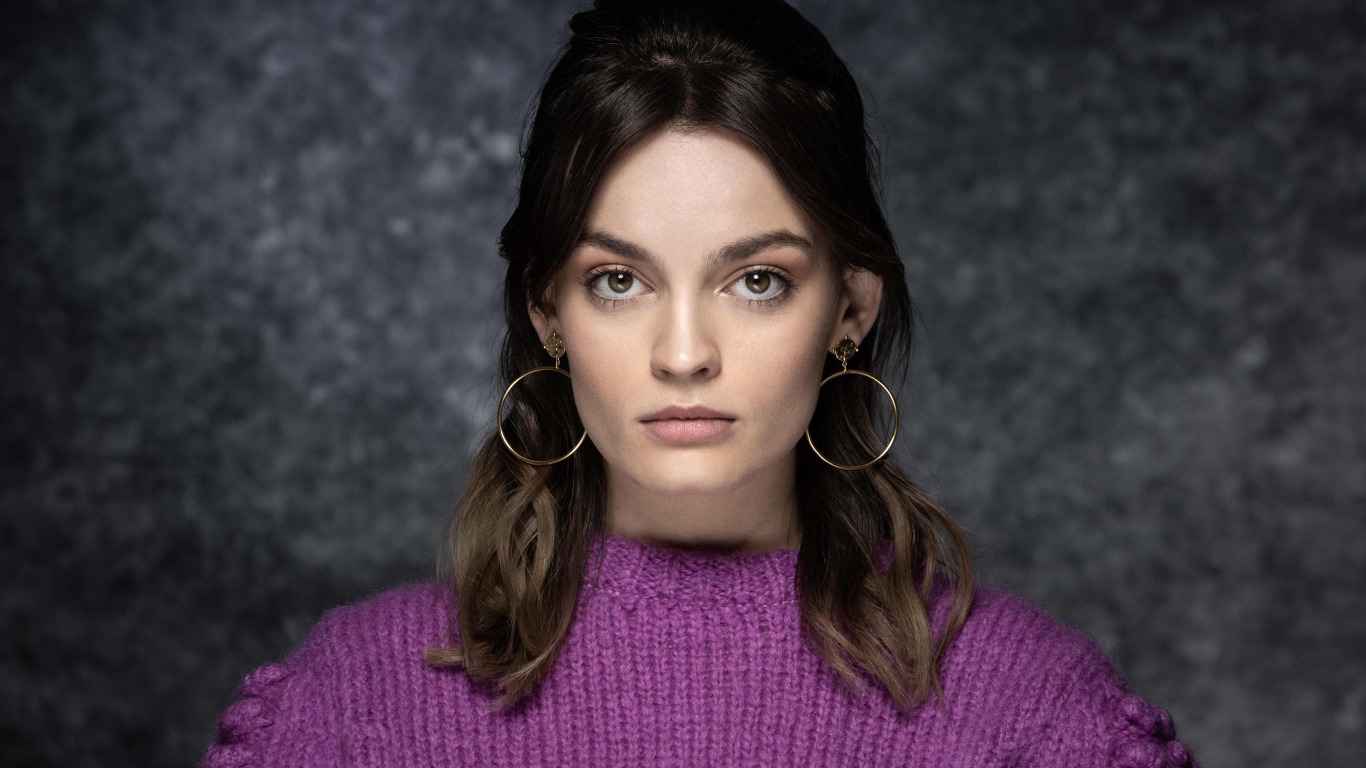 Актриса Эмма Маккей в сиреневом свитере на сером фоне