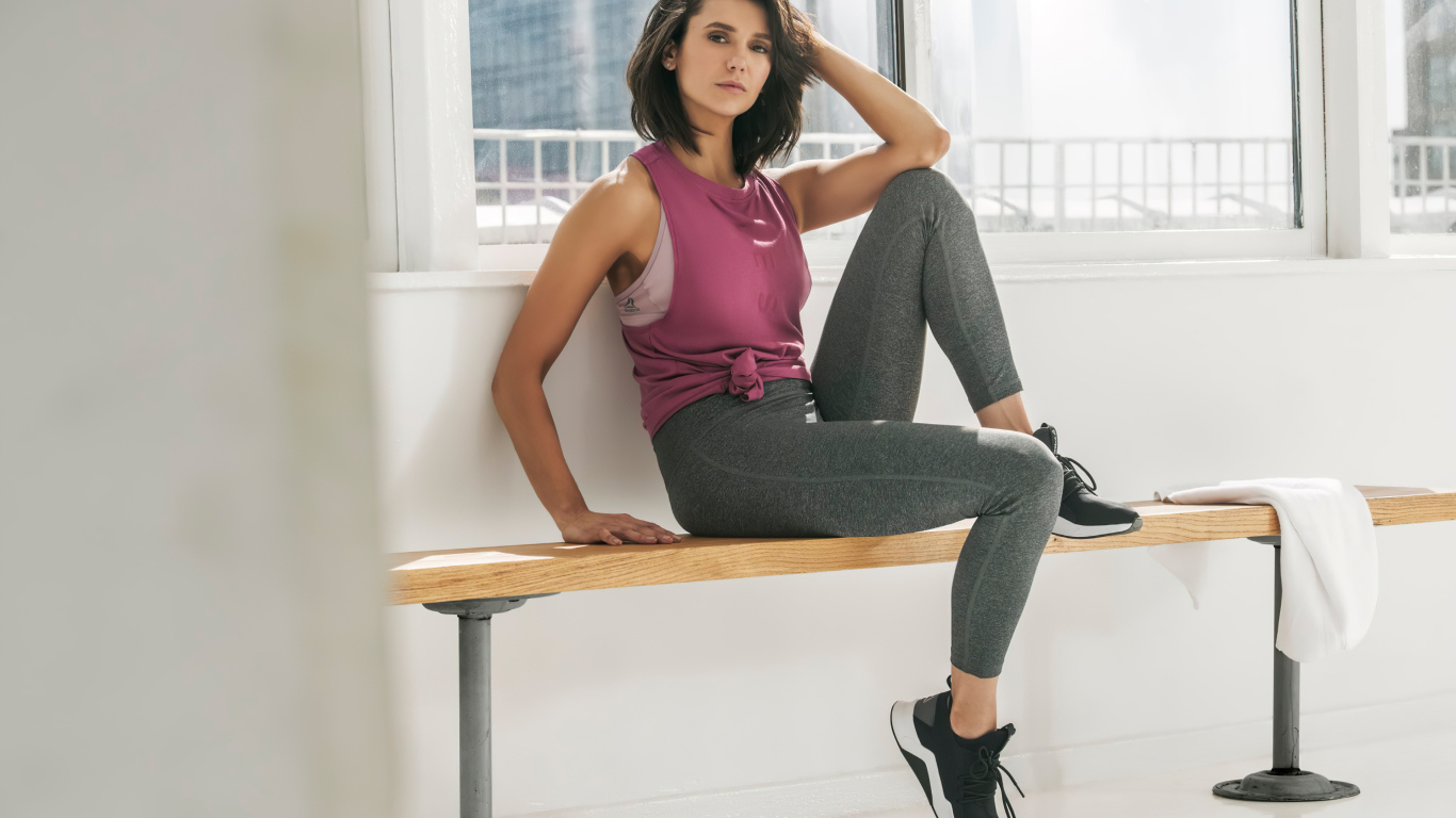 Актриса Нина Добрев сидит на лавке в спортивном костюме