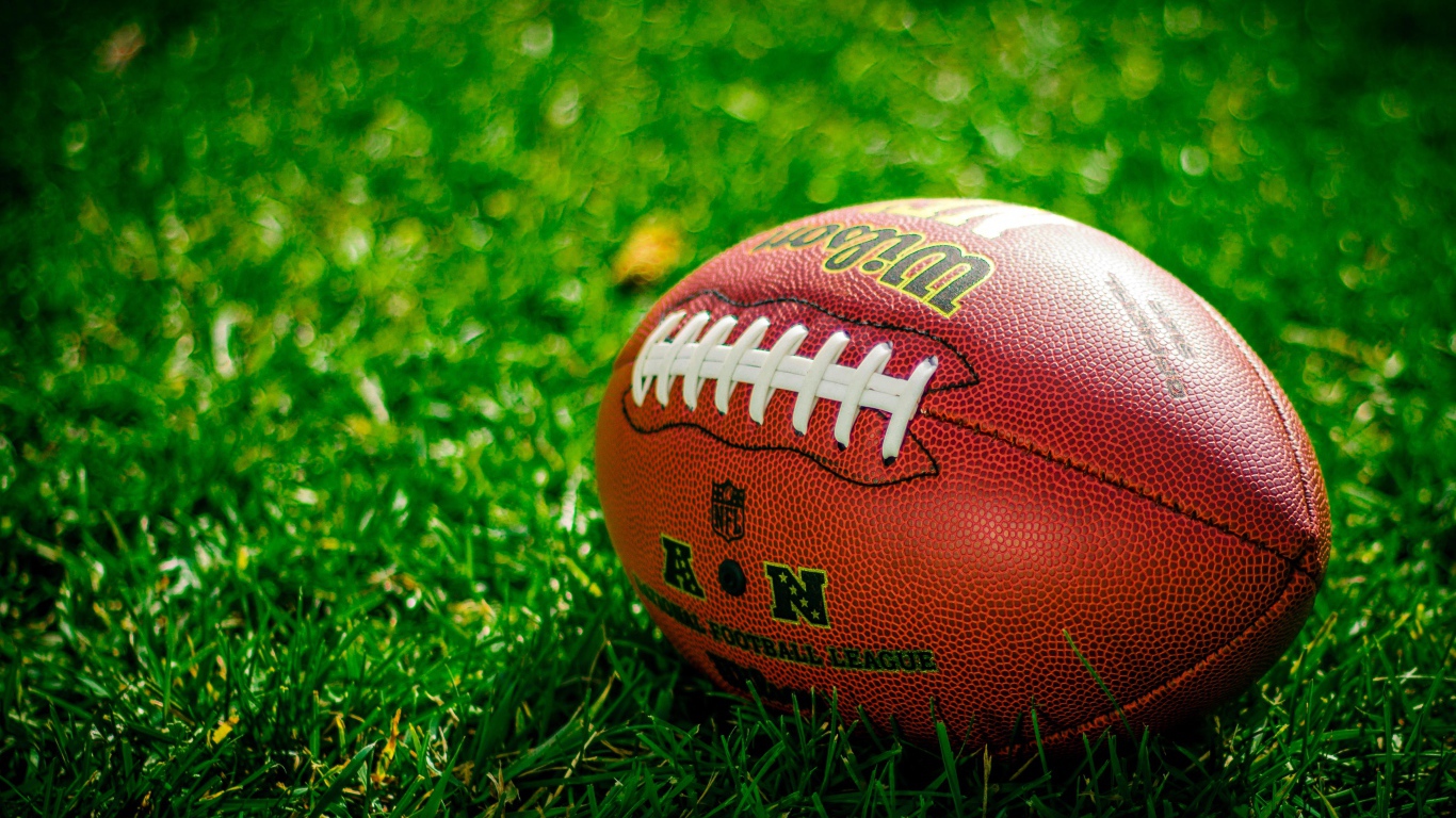 Мяч для американского футбола лежит на зеленой траве 